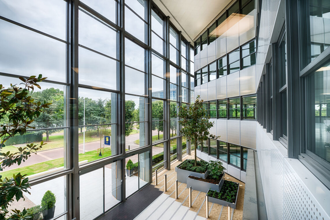 A beautiful open space spanning three floors with planted greenery metaphorically blurring the line between indoor construction and outdoor nature